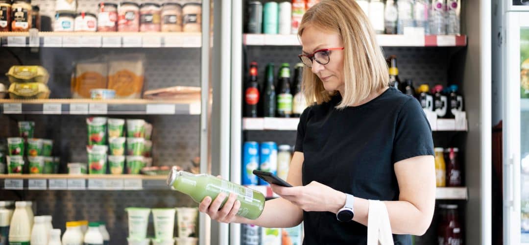 femme avec son téléphone qui lit l'étiquette d'un produit alimentaire